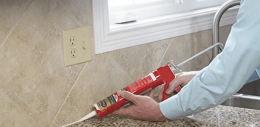 Handyman applying caulk along a kitchen backsplash and countertop seam in West Palm Beach, FL