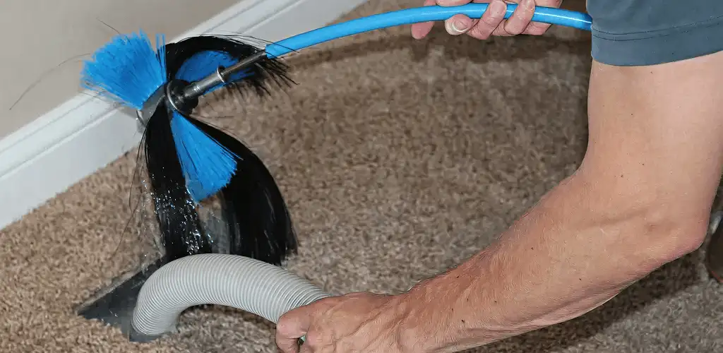 Dryer vent cleaning technician brushing lint from a vent line in West Palm Beach, FL