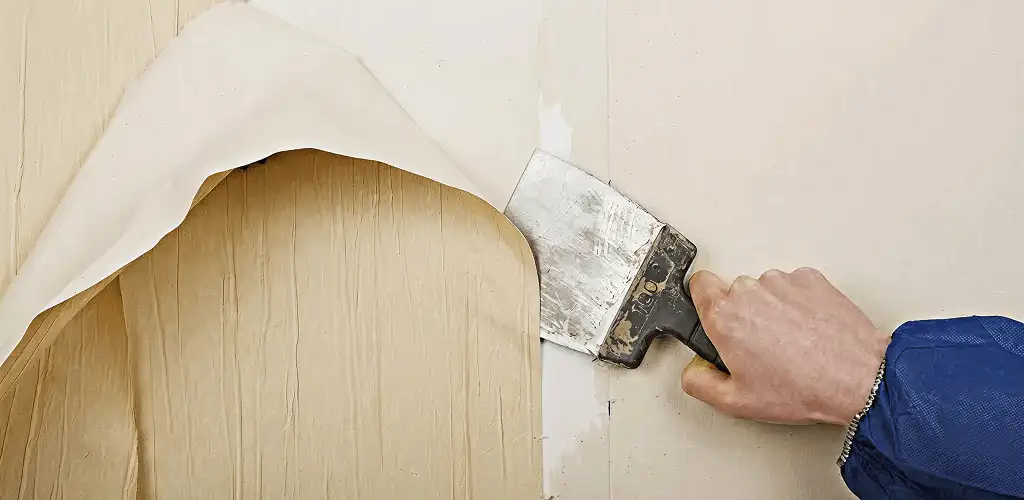 Handyman removing wallpaper with a scraper for wall preparation in West Palm Beach, FL