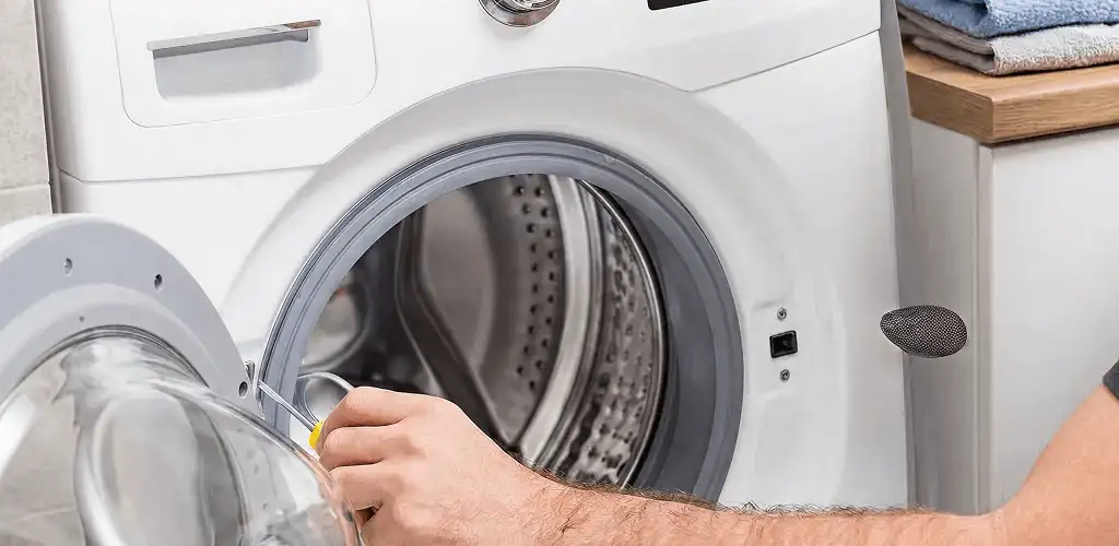 Handyman repairing a front-load washing machine and inspecting the drum in West Palm Beach, FL