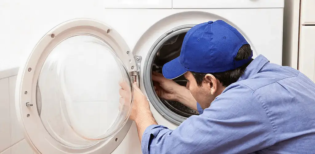 Washing machine repair handyman inspecting a front-load washer drum in West Palm Beach, FL